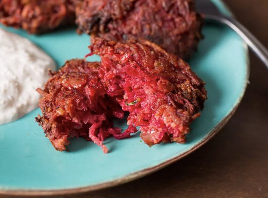 Crispy beet fritters with a vibrant red center served on a turquoise plate with a dollop of creamy dip.