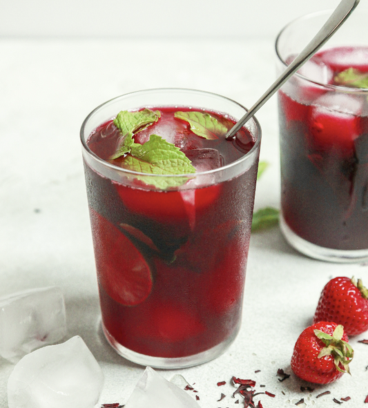 Refreshing hibiscus iced tea with strawberries, lime, and mint leaves — perfect for cooling down on hot days.