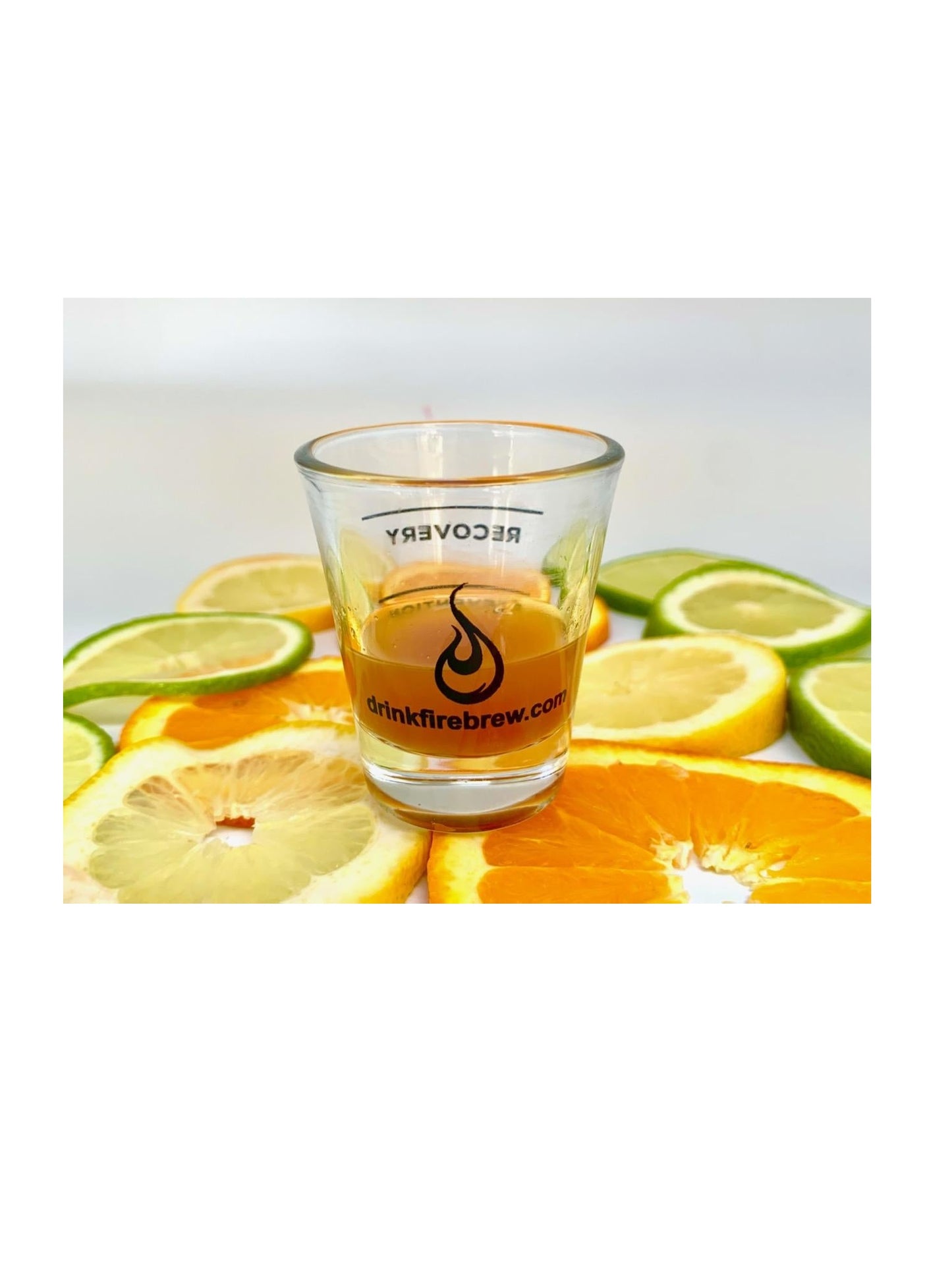 A Fire Brew wellness shot in a branded glass surrounded by fresh citrus slices for garnish.