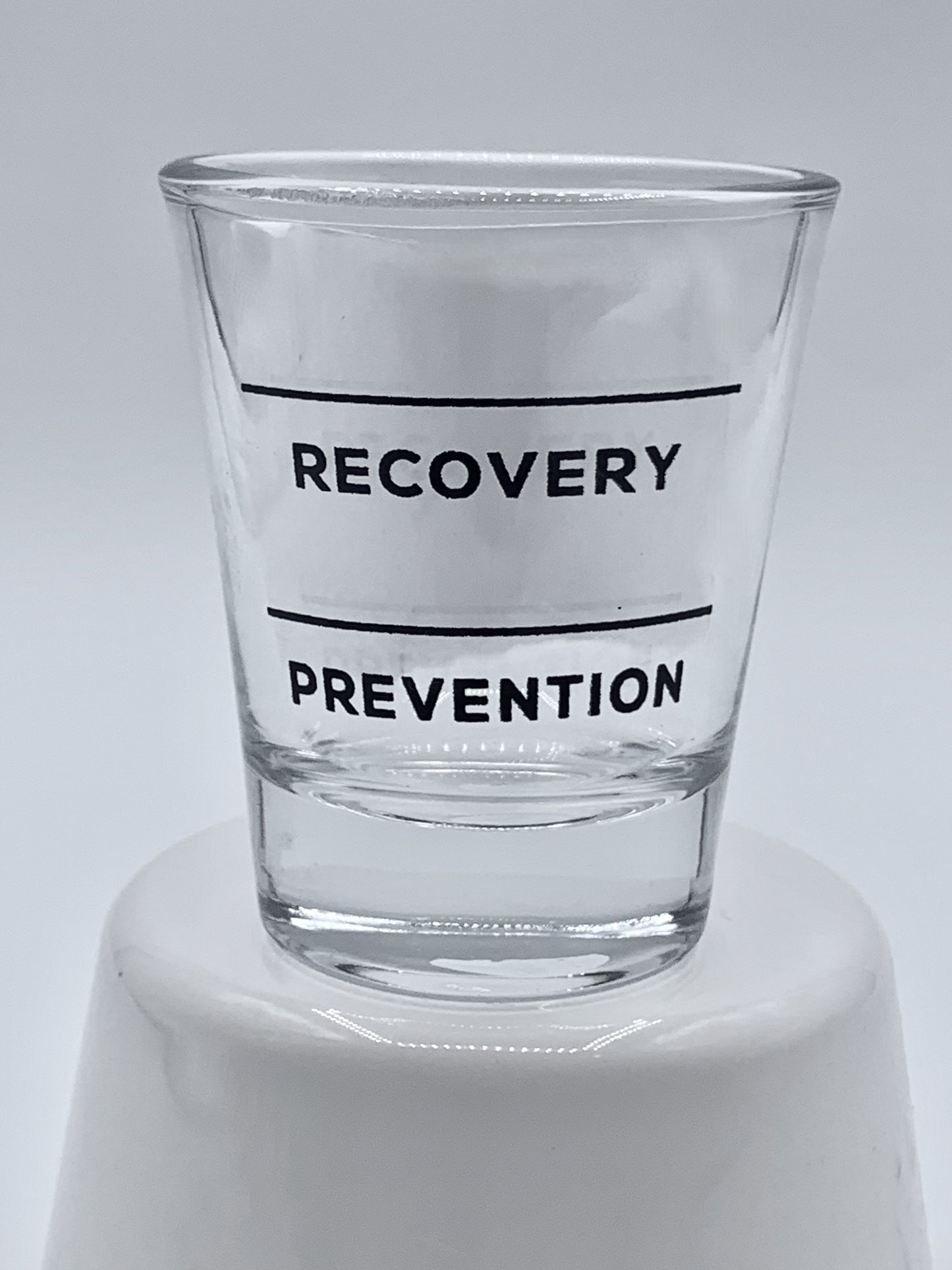 Clear Fire Brew shot glass with black text "Recovery" and "Prevention" on a white background.