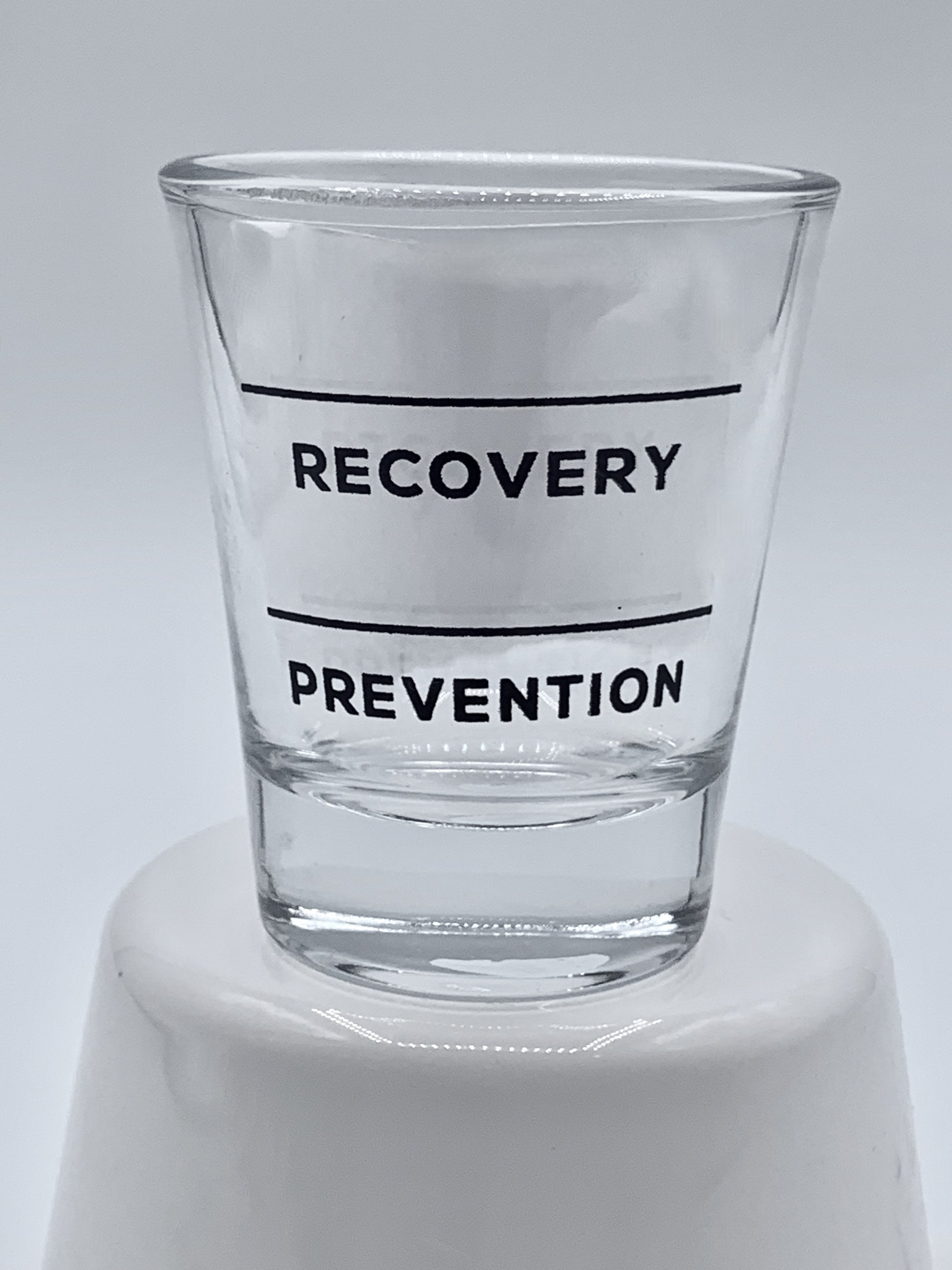 Clear Fire Brew shot glass with black text "Recovery" and "Prevention" on a white background.