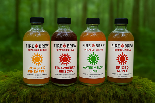 Four Fire Brew Apple Cider Vinegar Shrubs in assorted flavors shown outdoors on a mossy surface.