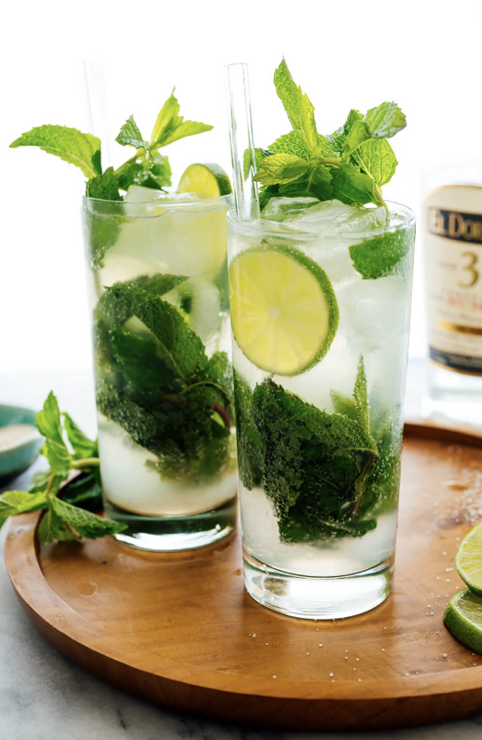 Refreshing mojitos with mint, lime, and rum served over ice—perfect for cooling off on a hot day.