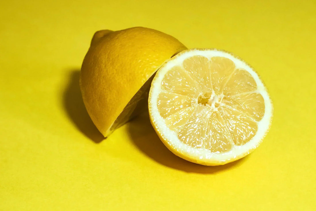 Fresh lemon cut in half, showcasing its juicy interior, placed on a bright yellow background for a vibrant and zesty look.