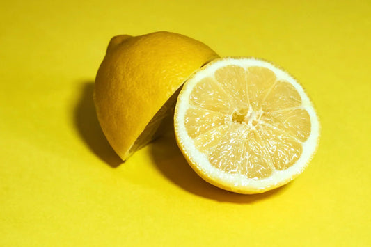 Fresh lemon cut in half, showcasing its juicy interior, placed on a bright yellow background for a vibrant and zesty look.